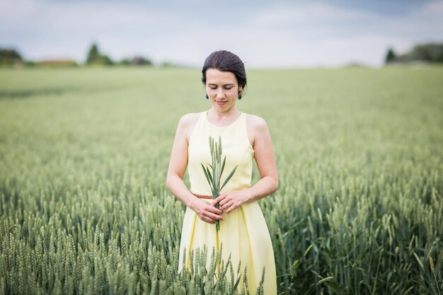 Lifestyle-portret van jonge stijlvolle vrouw die door een tarweveld loopt