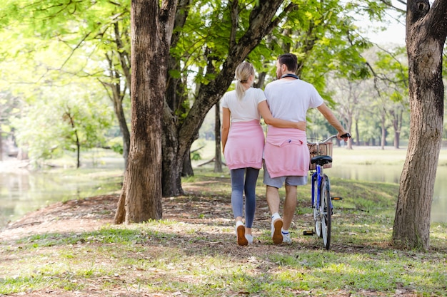 Photo lifestyle romantic people walking their bike along happily talking in park