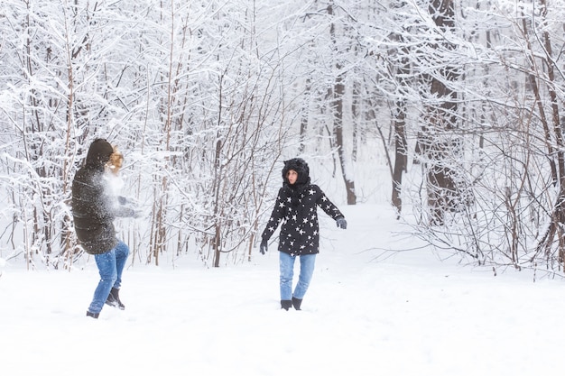 ライフスタイル、季節、レジャーのコンセプト-ウィンターパークで雪だるま式に遊ぶ面白いカップル。