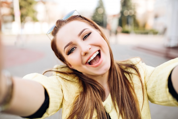 Lifestyle self-portrait of hipster woman wearing stylish bright outfits