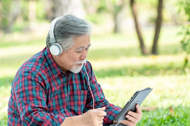 ライフスタイルの年配の男性は、白い背景で隔離のイヤホンヘッドフォンで音楽を楽しんで幸せに感じます