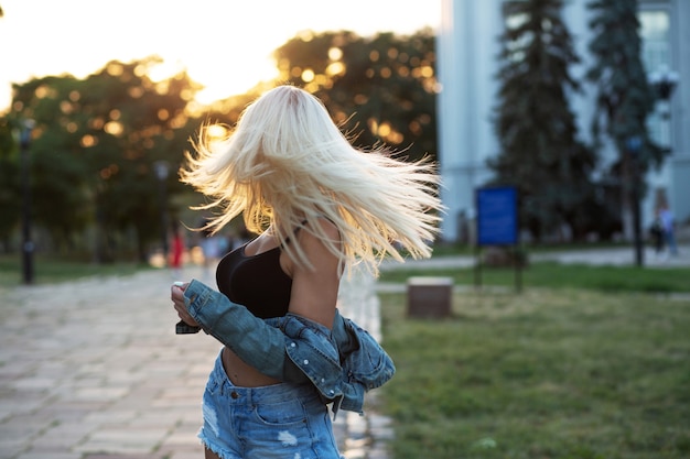 Lifestyle shot van een mooie vrouw met weelderig haar in de wind die bij zonsondergang op straat loopt Ruimte voor tekst