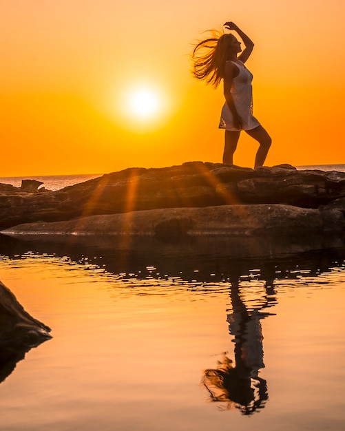 Foto lifestyle, silhouet van een jonge blonde aan de kust bij een zonsondergang