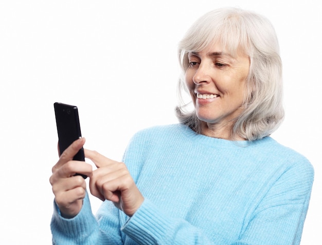 ライフスタイルのtehnologyと人々は白い背景で隔離のスマートフォンのテキストメッセージで年配の女性を概念します。