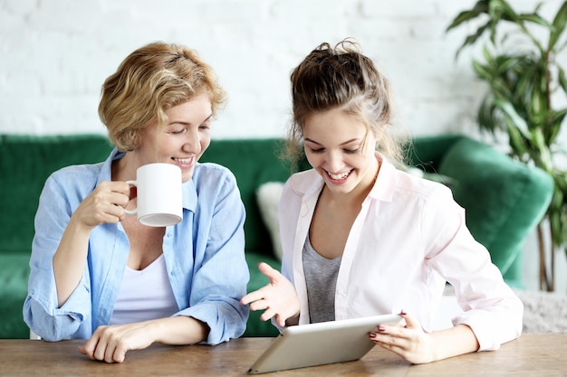 Lifestyle tehnology and people concept mother and adult daughter using tablet computer at home