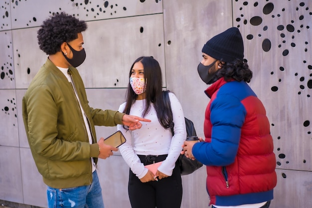 Lifestyle, three friends talking in the street and having fun with face masks.