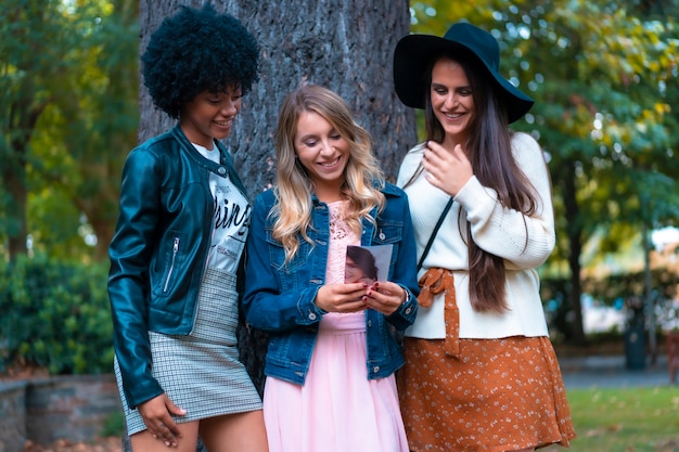 Lifestyle. Three good friends in a fall session in a tree, a blonde, a brunette and a Latin girl with afro hair