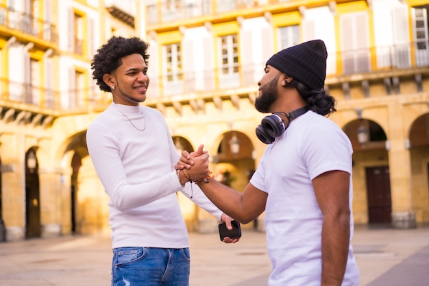 Lifestyle, twee zwarte Latino-vrienden die zwaaien terwijl ze elkaar op straat ontmoeten