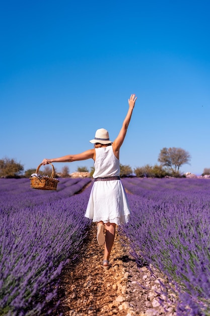 Lifestyle a woman in a summer lavender field in a white dress enjoying nature