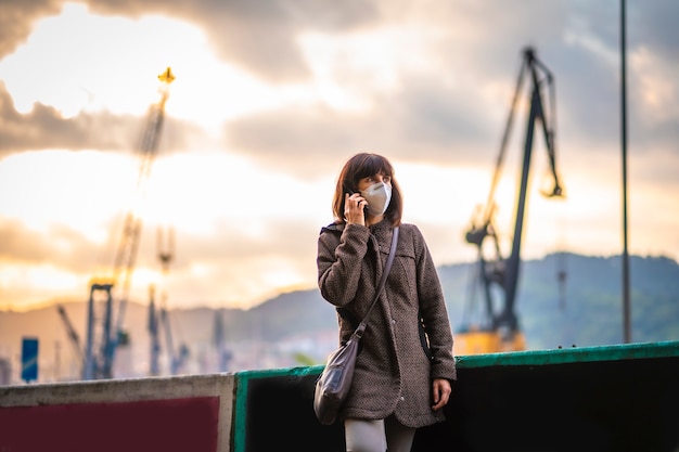 Photo lifestyle of a young brunette with mask talking on the phone. first walks of the uncontrolled covid-19 pandemic