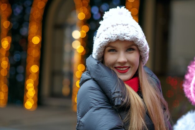 Lifetyle portrait of positive woman with red lips having fun in winter holidays at the background of bokeh. Space for text