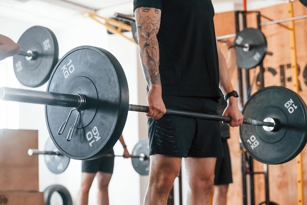 Bilanciere di sollevamento un gruppo di giovani sportivi ha una giornata di crossfit al chiuso in palestra