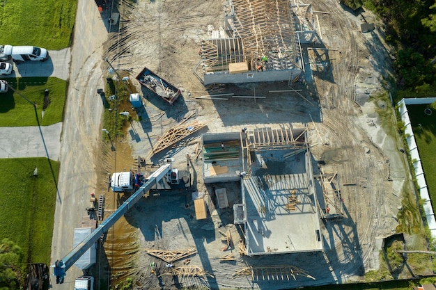 フロリダ郊外の木造軸組未完成住宅の屋根工事に取り組む吊り上げクレーン車と建設業者 住宅開発コンセプト