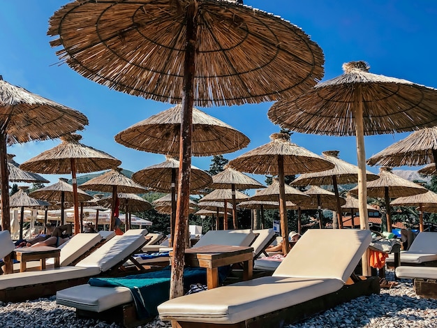 Ligbedden en parasols op een Europees strand op een achtergrond van blauwe lucht. Toerisme concept.