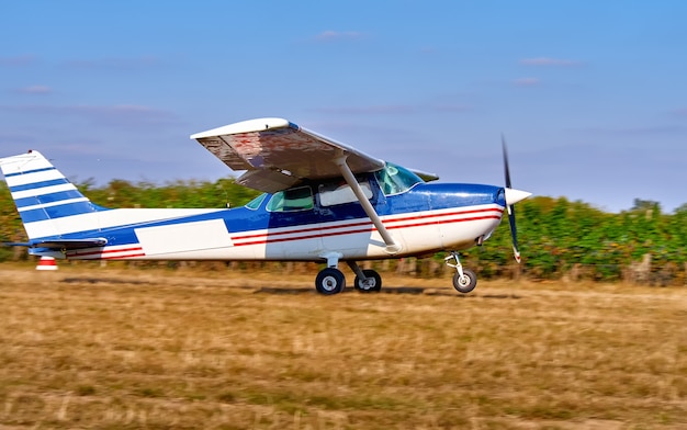 軽飛行機がブドウ園近くの畑で離陸します。晴れた夏の日、人々は見守り、植えます。