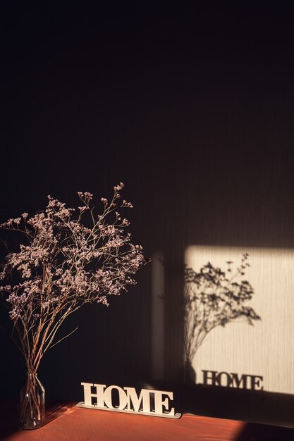 사진 빛과 비문 벽에 창문을 통해 그림자 집과 투명 꽃병에 말린 된 꽃다발입니다.