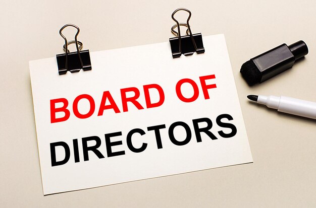 明るい背景、黒のオープンマーカー、黒のクリップには、BOARD OFDIRECTORSというテキストが付いた白い紙があります。