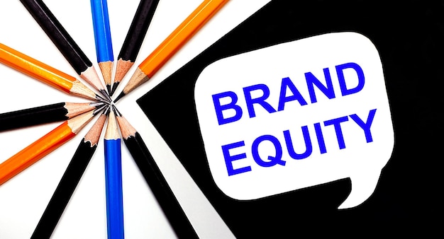 Foto su sfondo chiaro matite multicolori e su sfondo nero un cartoncino bianco con la scritta brand equity