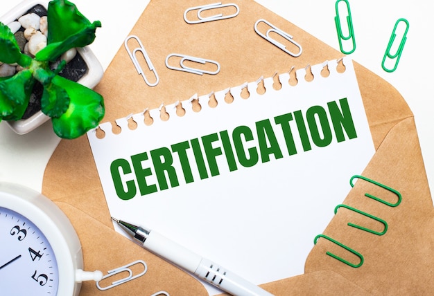 On a light background, an open envelope, a white alarm clock, a green plant, white and green paper clips, a white pen and a sheet of paper with the text CERTIFICATION