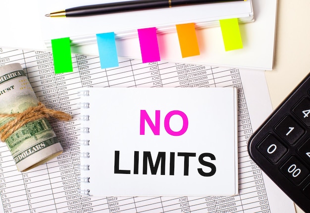 On a light background a pen dollars a notebook with the text NO LIMITS and bright stickers Business concept