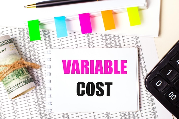 明るい背景にペン ドル テキスト VARIABLE COST と明るいステッカー ビジネス コンセプトのノート