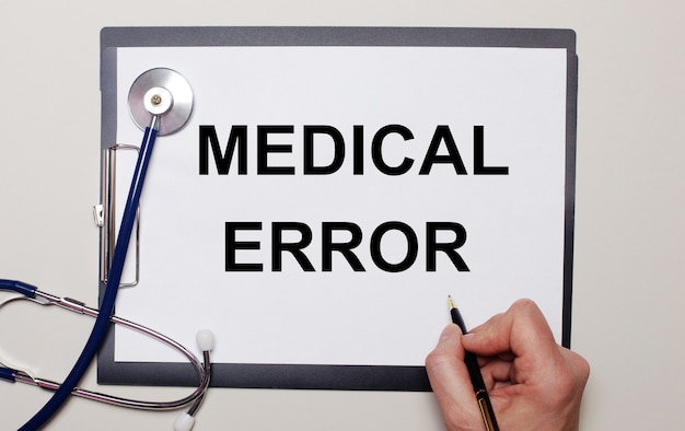 Photo on a light background, a stethoscope and a sheet of paper, on which a man writes medical error.