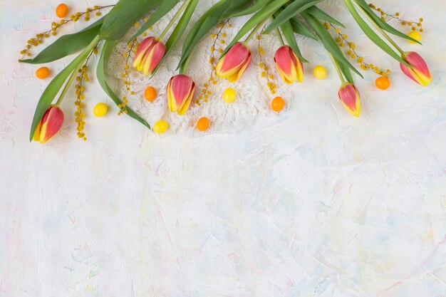 on a light background tulips, mimosa, feather, eggs 