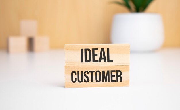 На светлом фоне деревянные кубики и деревянный брусок с текстом IDEAL CUSTOMER. Вид сверху