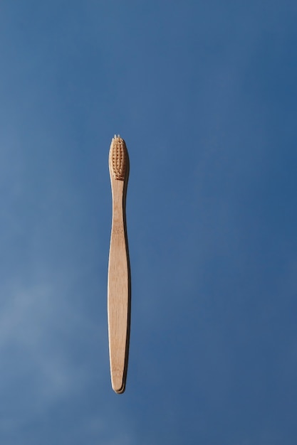 Light bamboo toothbrushes are reflected in the mirror against the blue sky.