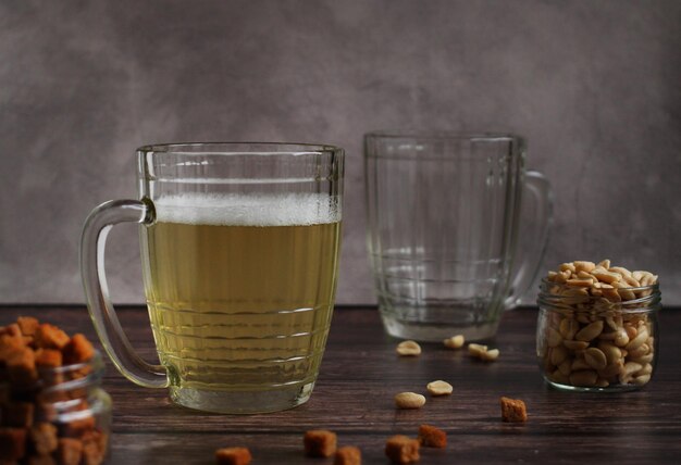 Light beer in a glass mug with crackers and peanuts on a dark background