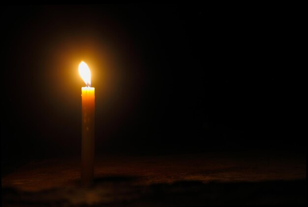 Light for a better life One yellow candle on floor burns against the black background with copy space