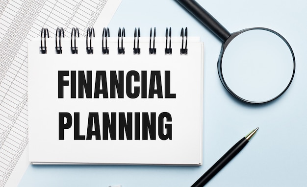 Photo on a light blue background, reports, a magnifying glass, a pen and a notebook with the text financial planning. business concept. flat lay.