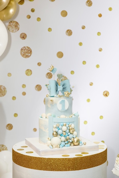 弓心の冠と風船で飾られた明るい青い誕生日ケーキ