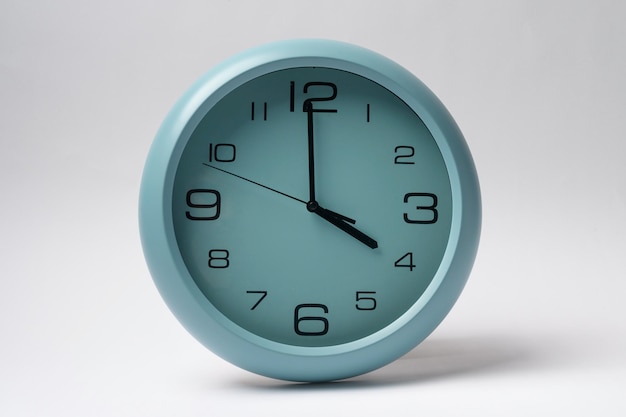 Light blue clock hanging on white wall