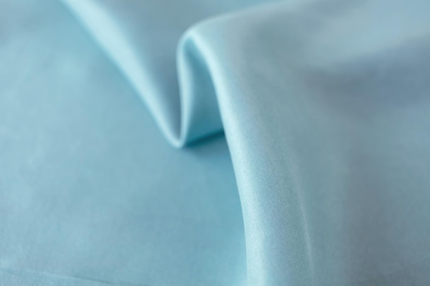 Light blue color natural silk draped in folds top view satin fabric texture pastel shade