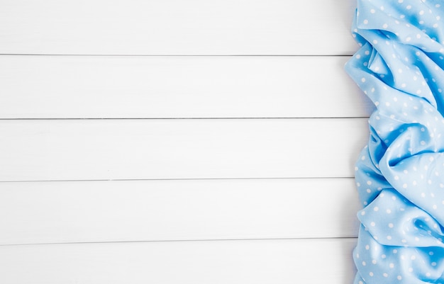 Light blue polka dots folded tablecloth over bleached wooden table. Top view image. Copyspace for your text.