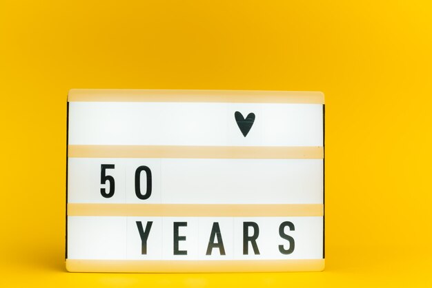 light box with text, 50 YEARS, on yellow wall