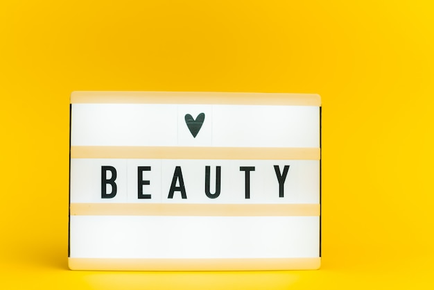 light box with text, BEAUTY, on yellow wall