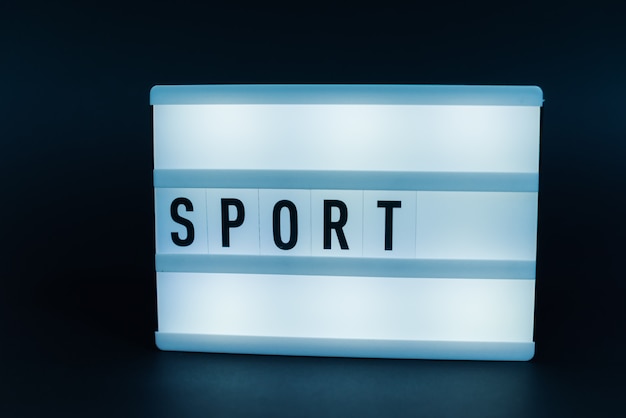 light box with text, SPORT, over dark wall