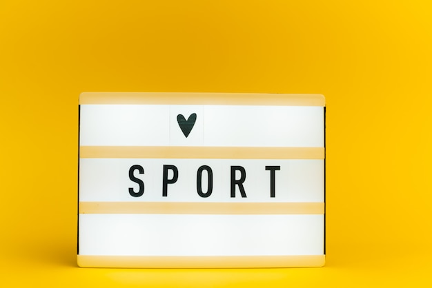 Light box with text, sport, on yellow wall