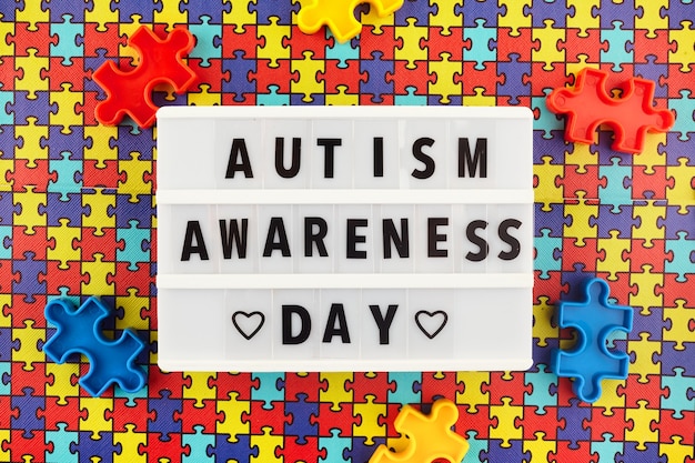 Photo light box with world autism awareness day text on colored puzzle background. top view