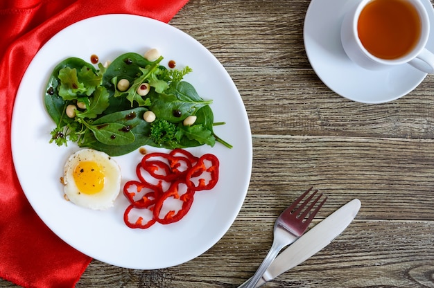 Colazione leggera - uova di quaglia, insalata verde, peperone dolce e una tazza di tè su un tavolo di legno. vista dall'alto. cibo salutare. nutrizione appropriata.