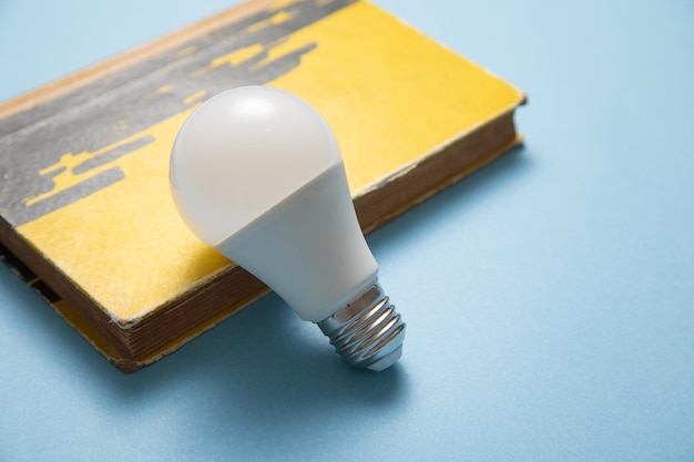 Light bulb and book on the blue background Knowledge and wisdom