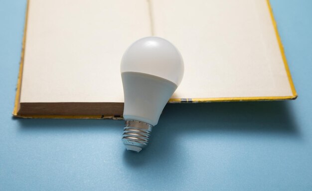 Photo light bulb and book on the blue background knowledge and wisdom