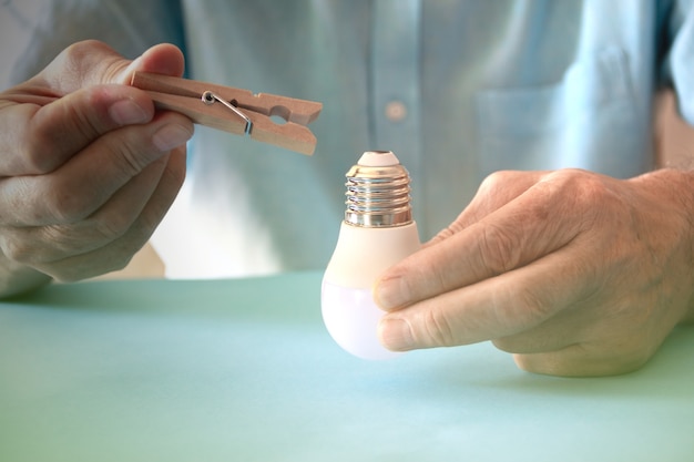 Light bulb caught with clothespins. Energy saving concept. Copy sopace. Selective focus.