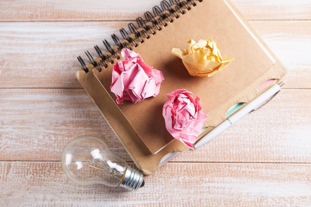 Light bulb, crumpled papers and notepad on the table