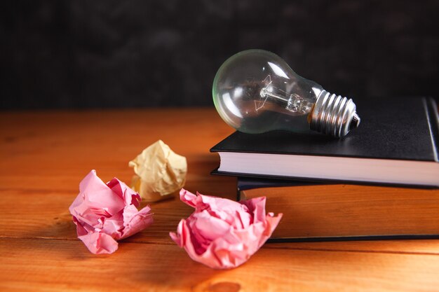 Photo light bulb, crumpled papers and notepad on the table