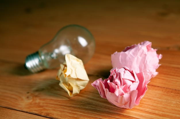 Light bulb and crumpled papers on the table