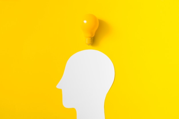 Photo light bulb over the cut out white human head on yellow background