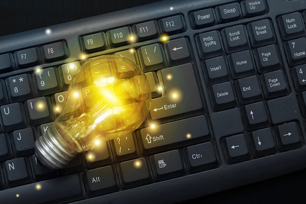 Photo light bulb glowing on pc keyboard